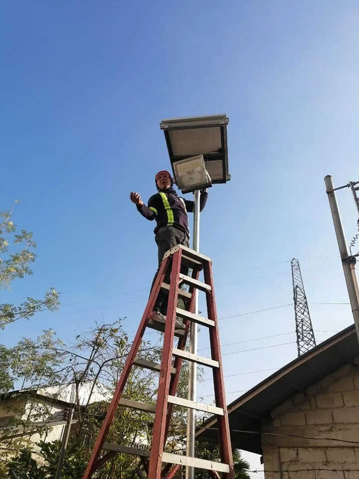 technician-on-ladder-installing-solar-street-light-with-panel